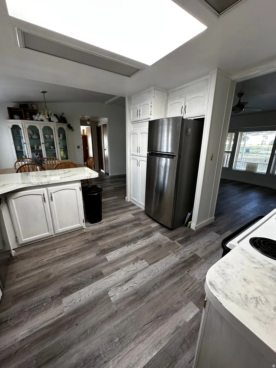 Kitchen featuring wood-finish flooring, white cabinetry, a stainless steel refrigerator, and recessed lighting