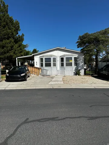 Single-story home featuring a covered carport, wood ramp access, and bay windows