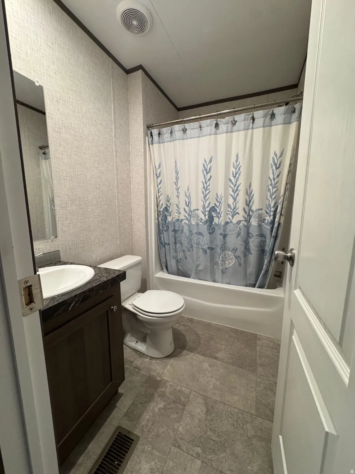 Full bathroom featuring a single vanity with an integrated sink, dark wood-finish cabinetry, and a dark countertop