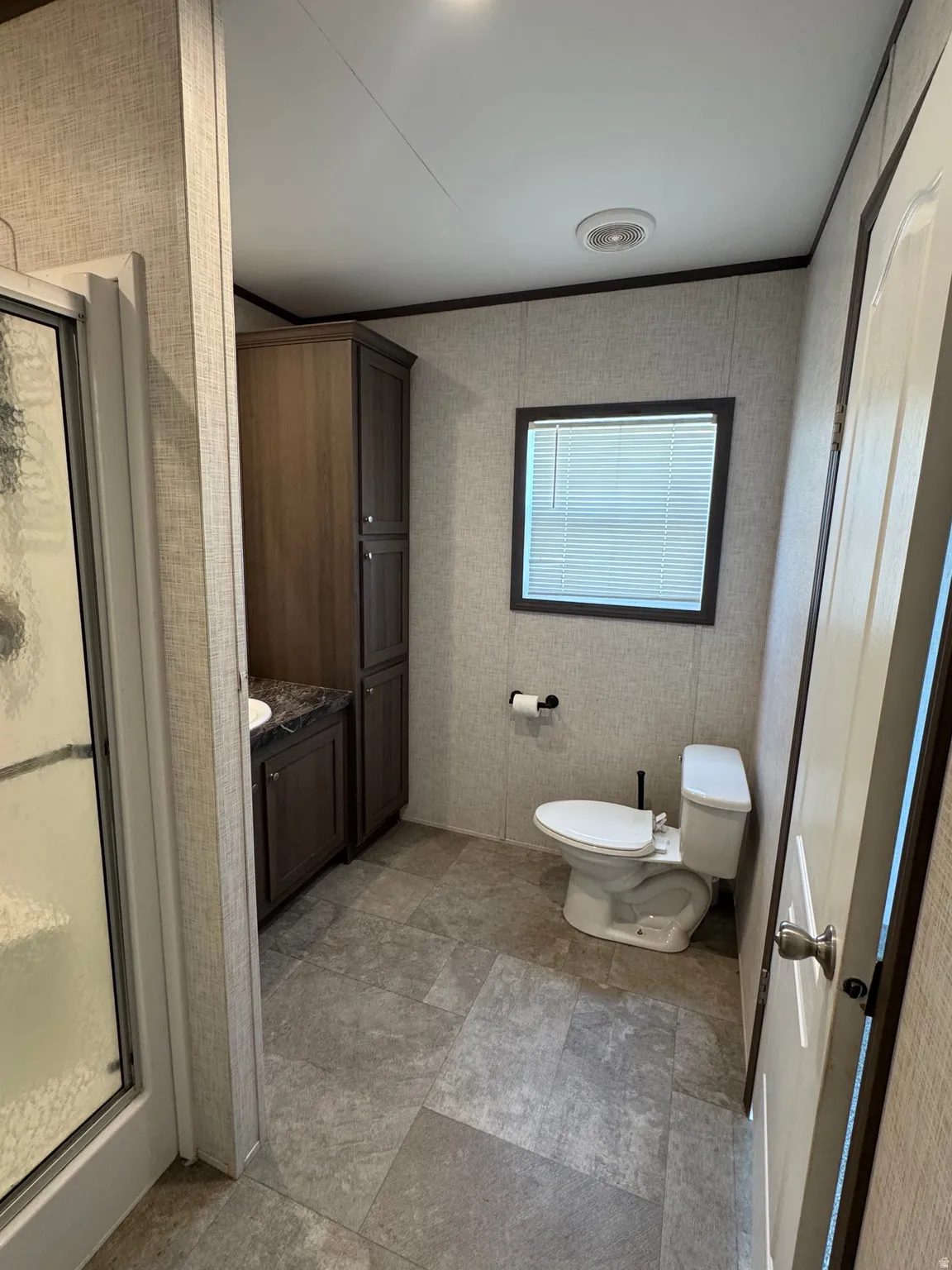Full bathroom featuring a shower enclosure with frosted glass, a toilet, and a vanity with a dark wood-finish cabinet