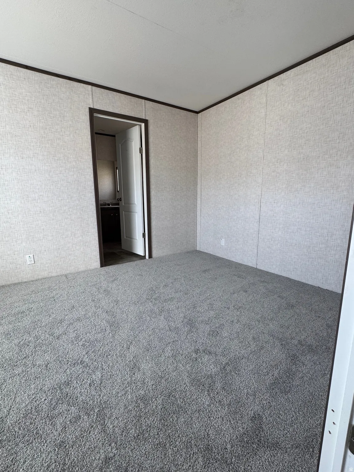 Spacious room featuring gray textured carpeting and light-colored wall panels