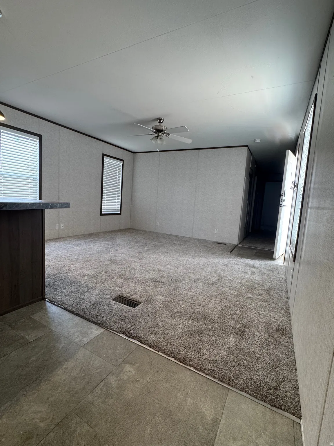Spacious room featuring neutral carpeting and a ceiling fan