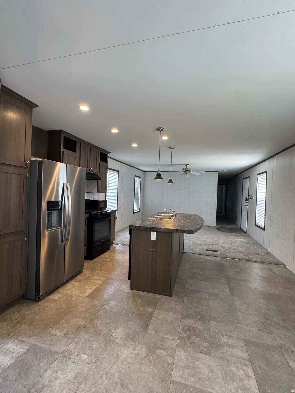 Kitchen with dark wood-finish cabinetry, stainless steel refrigerator, and a black range