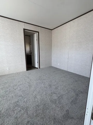 Spacious room featuring gray textured carpeting and light-colored wall panels
