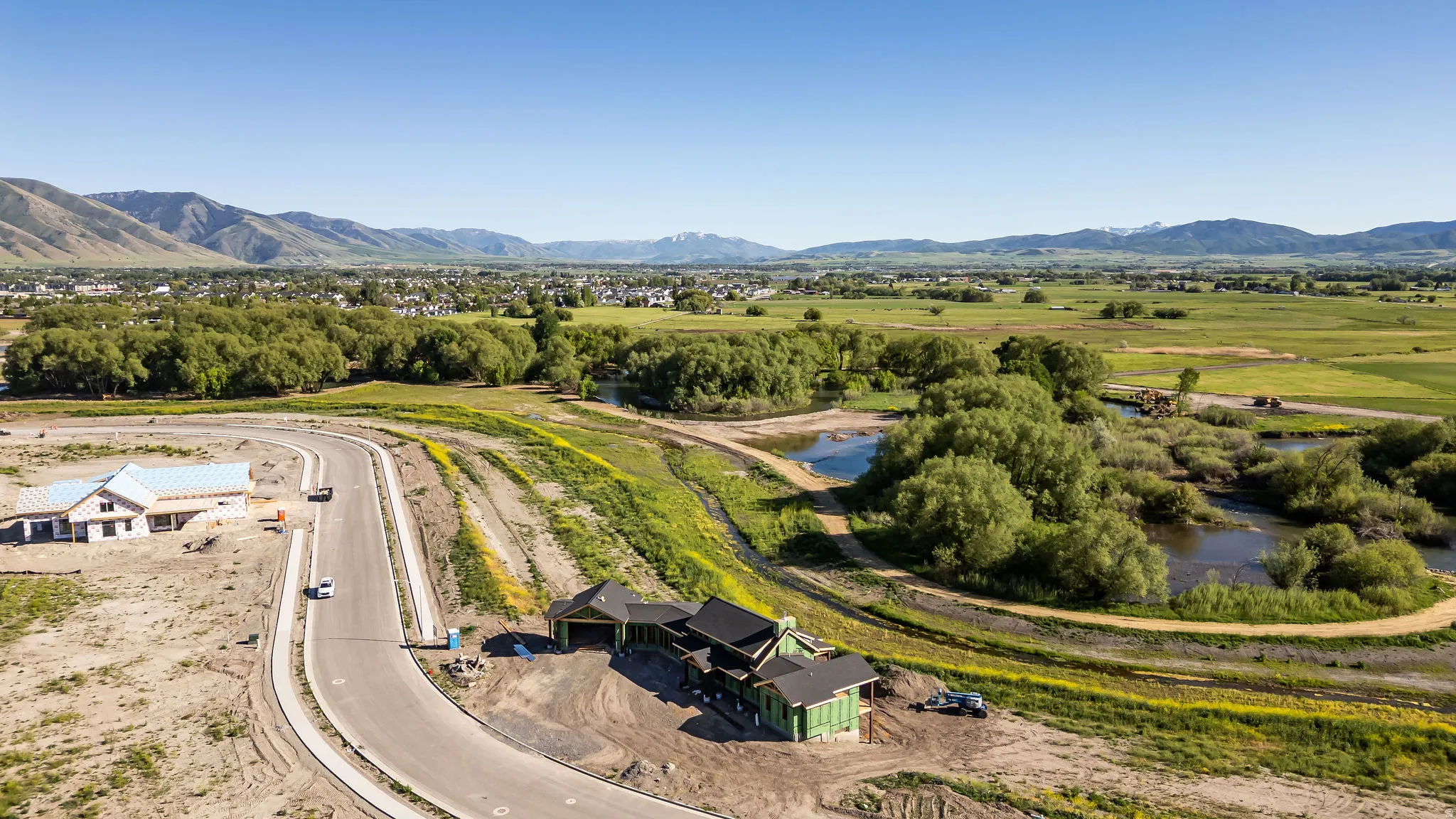 Expansive property with a paved road, developing residential structures, and natural water features