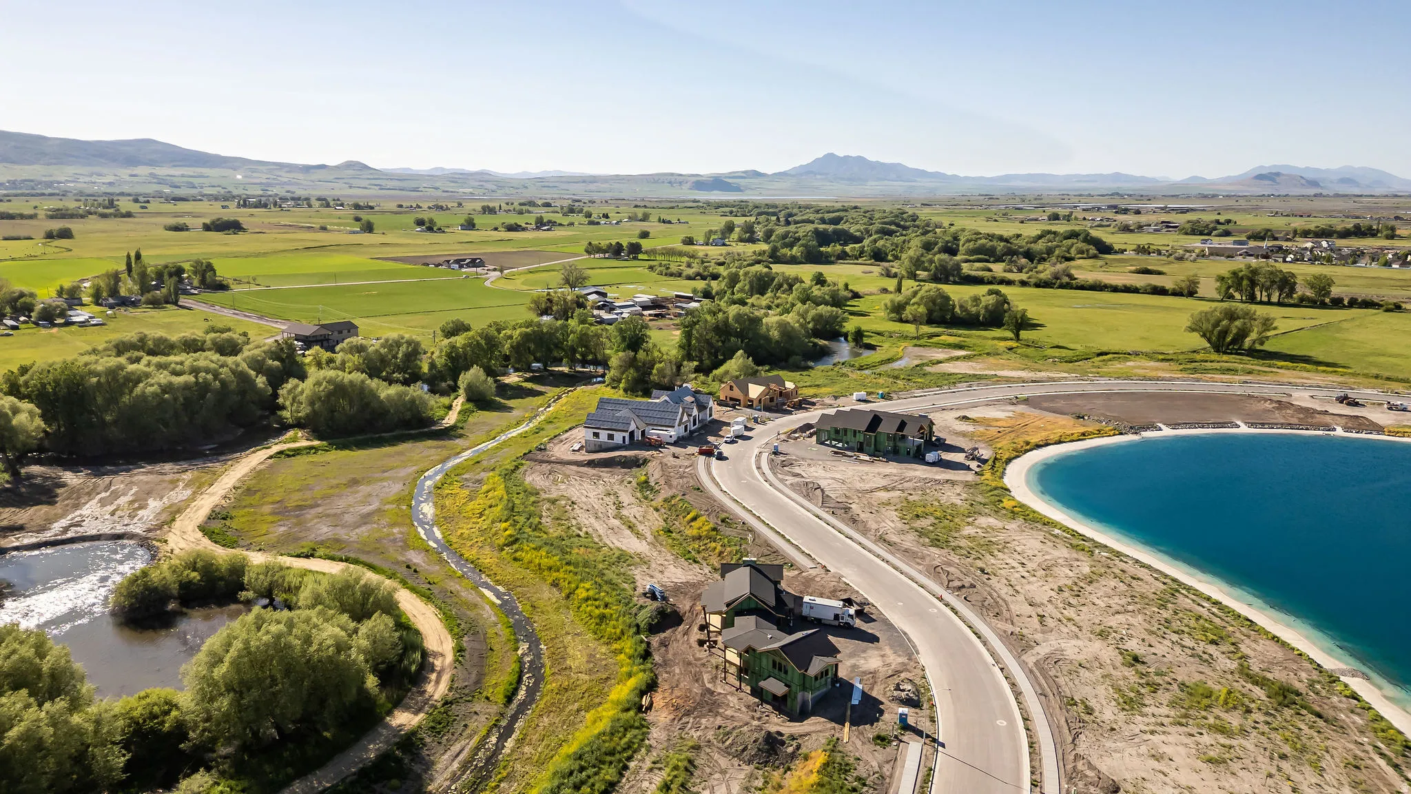 Newly constructed homes situated alongside a vibrant blue-water reservoir and paved roadway