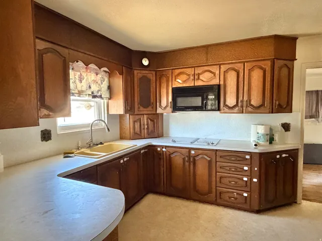 Kitchen featuring wood-finish cabinetry, light-toned countertops, and a built-in microwave