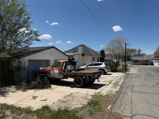 White siding garage with a gabled roof and attached concrete driveway