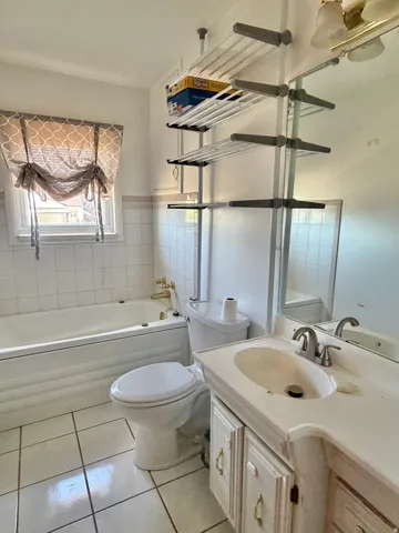 Bathroom with a built-in tub, white tiled flooring, a single-sink vanity, and a mounted mirror