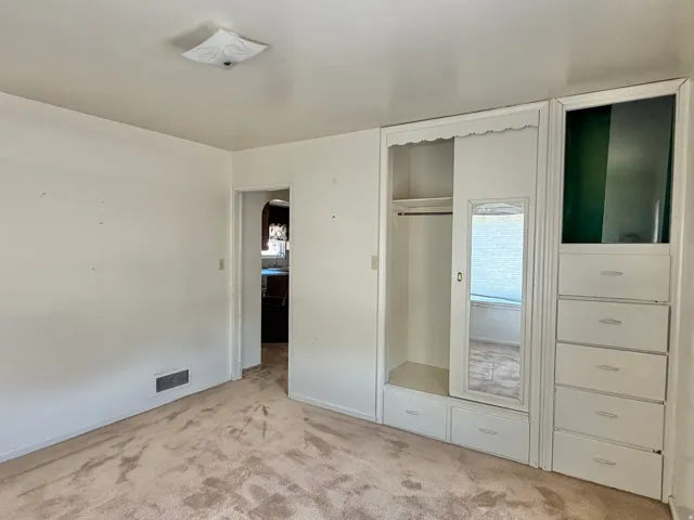 Recessed built-in cabinetry featuring a hanging rod, mirrored panel, and multiple storage drawers