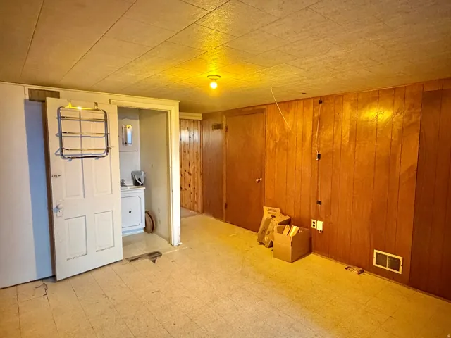 Interior space featuring wood-panel walls, a drop ceiling, and light-colored flooring