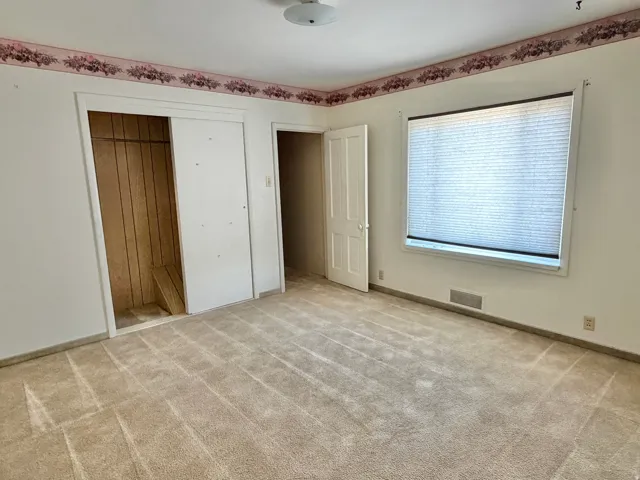 Carpeted interior space with a window featuring horizontal blinds