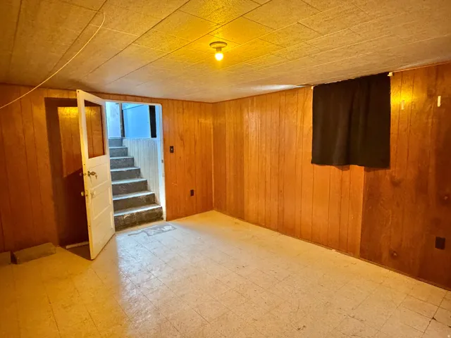 Finished room featuring wood paneling, tiled flooring, and a drop ceiling