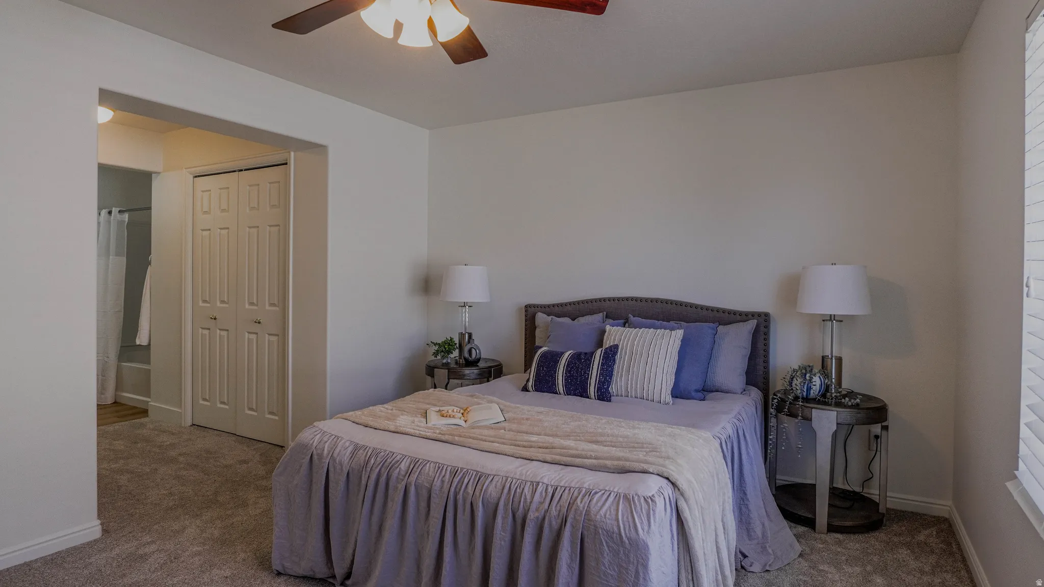 Carpeted room with a ceiling fan and an arched doorway revealing a bathroom with a shower-tub combination