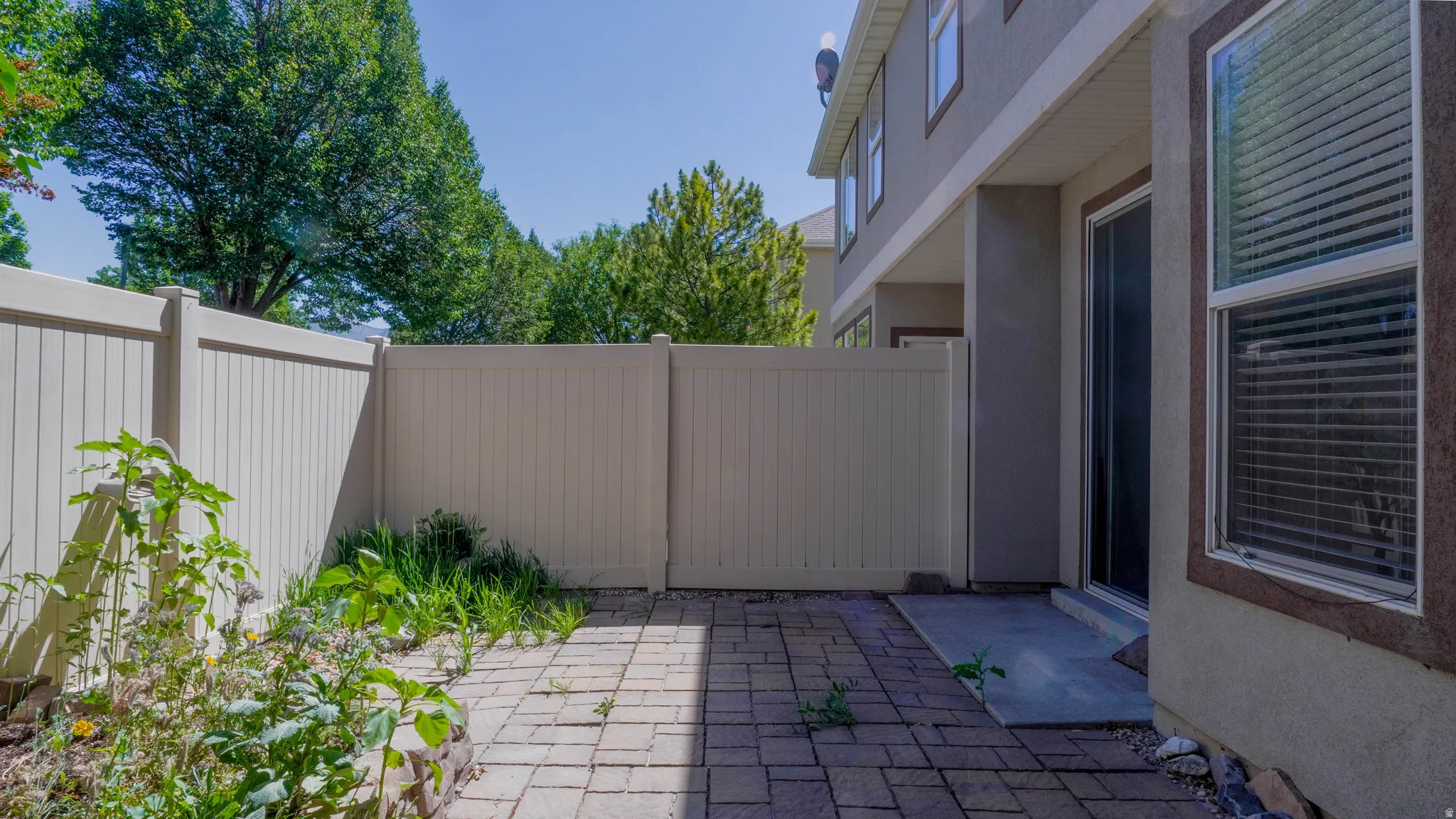 Private outdoor patio featuring a paver surface, vinyl fencing, and direct access to the interior via a sliding glass door