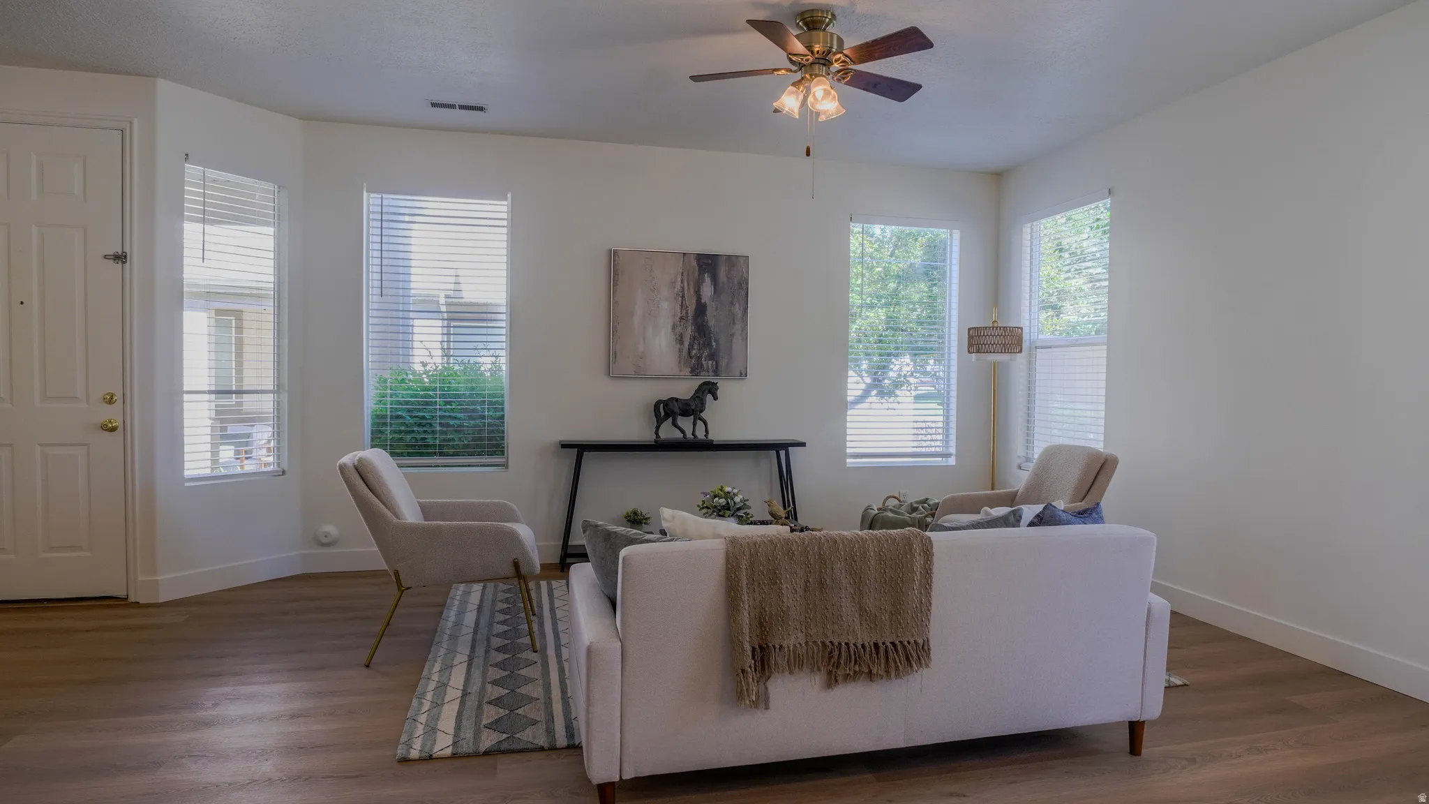 Spacious living area featuring wood-finish flooring, white walls, and a multi-paneled entry door