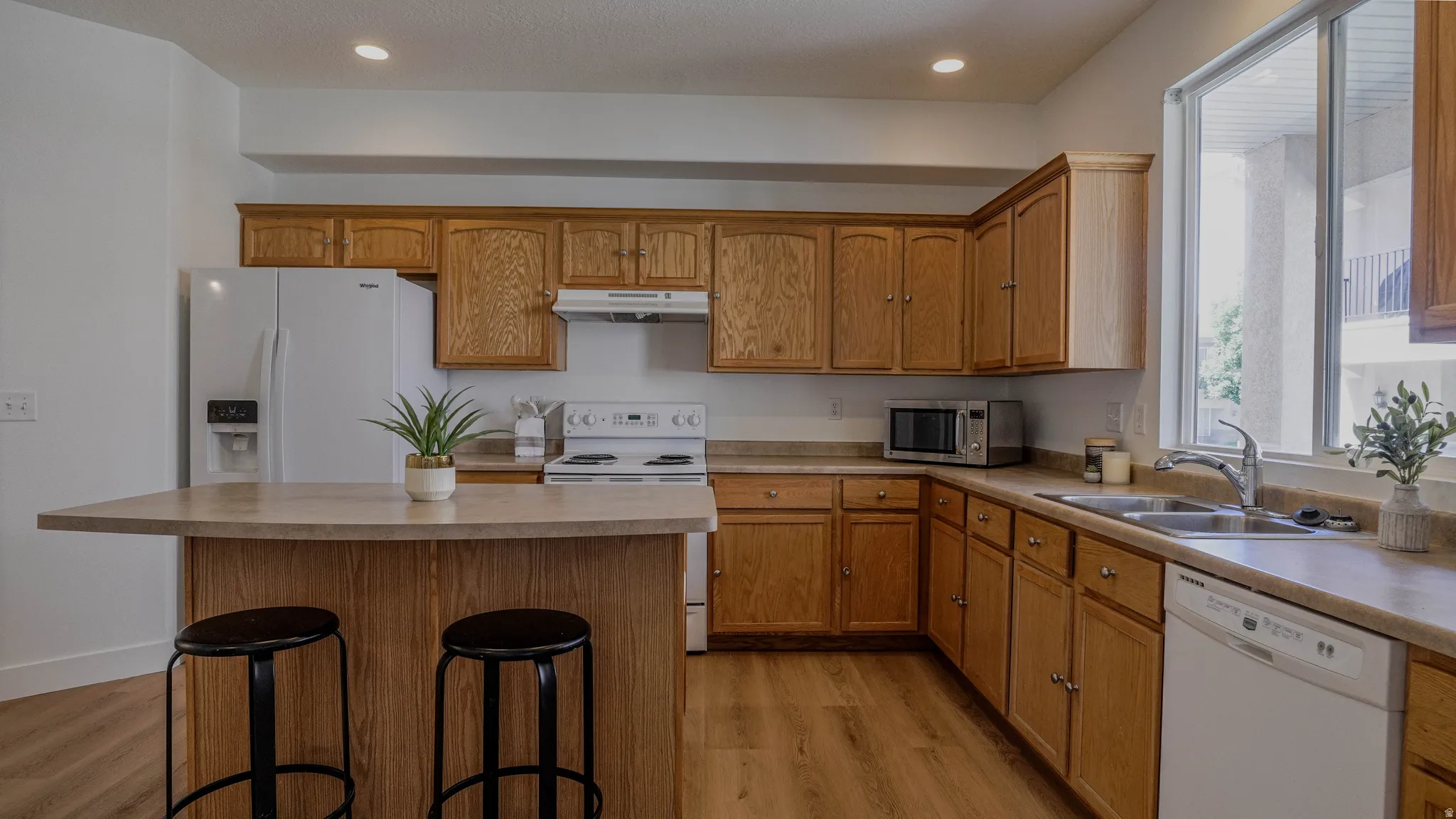 Kitchen featuring wood-finish cabinetry, light-toned countertops, and wood-finish flooring