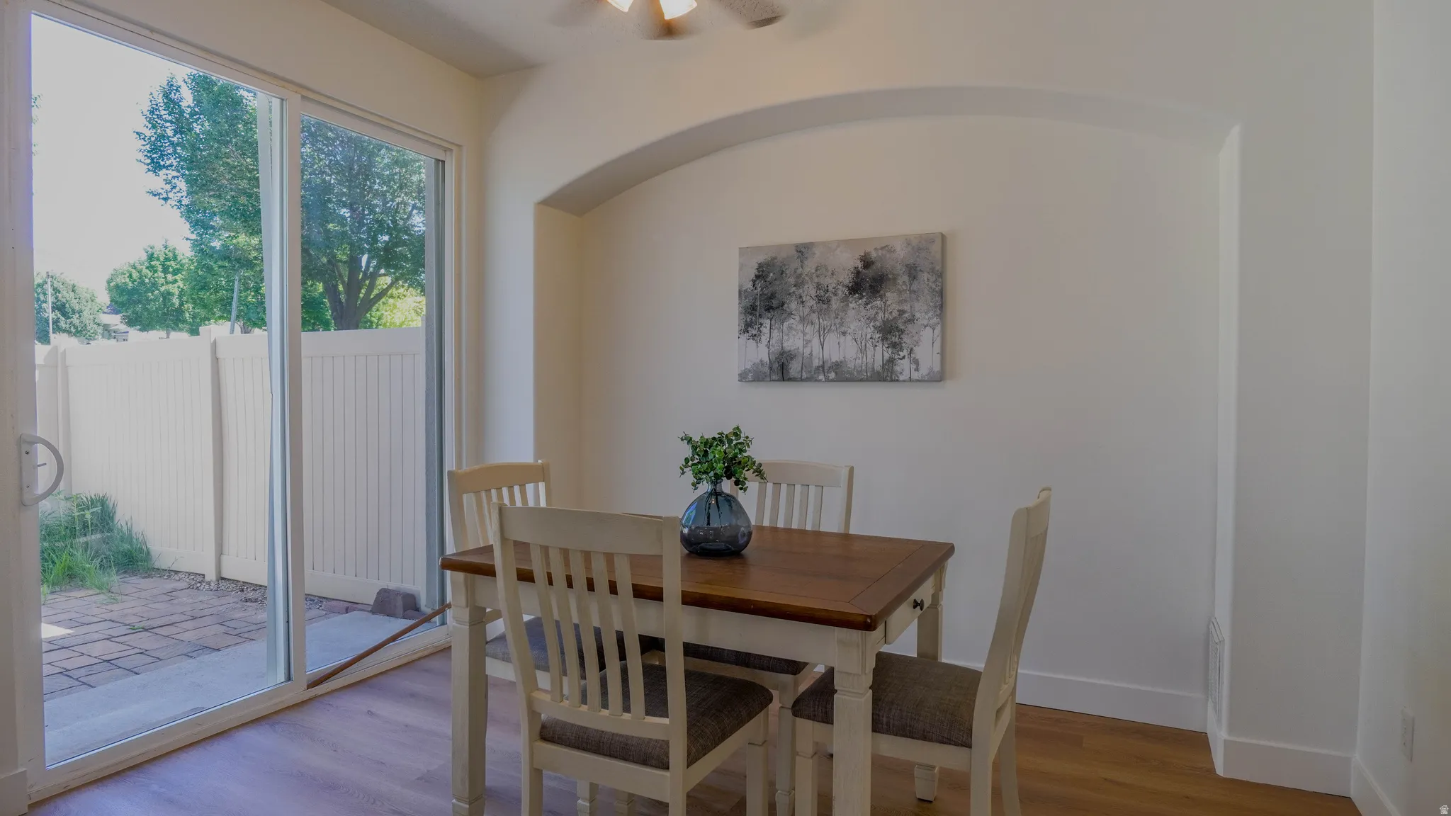Dining area featuring wood-finish flooring, an arched wall niche, and a sliding glass door opening to a paved patio