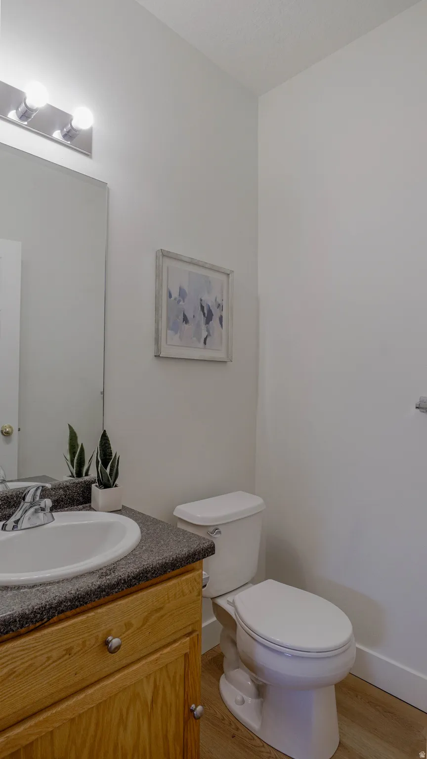 Bathroom vanity with a white basin, speckled countertop, and wood-finish cabinetry