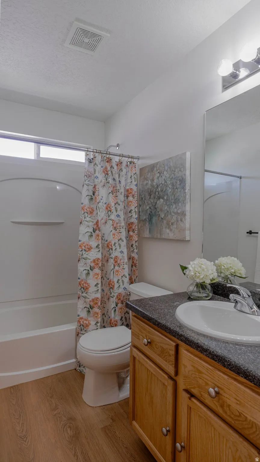 Bathroom featuring a vanity with a dark countertop and integrated sink, wood-finish cabinetry, and a mirrored wall