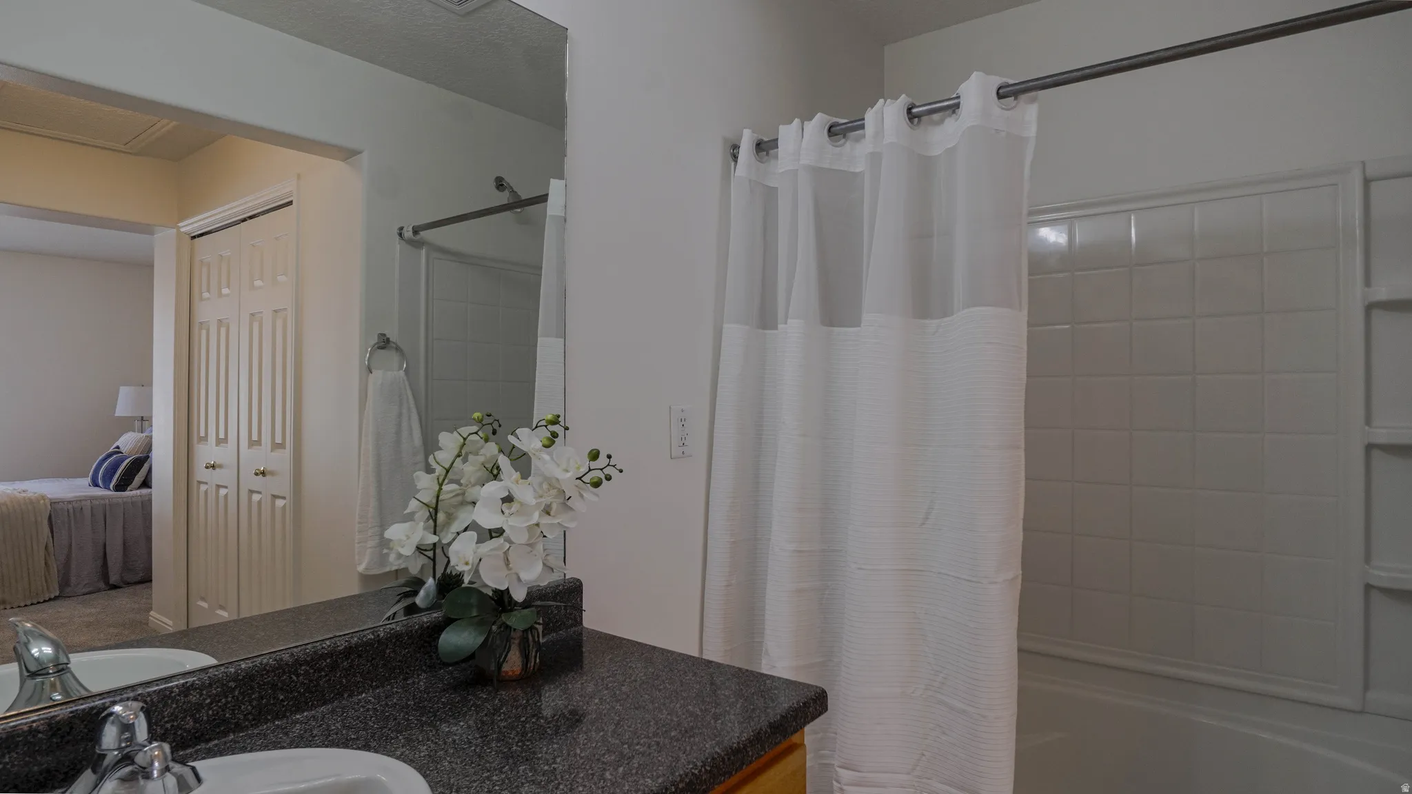 Bathroom featuring a shower-tub combination with white subway tile surround, granite-finish countertop, and integrated sink