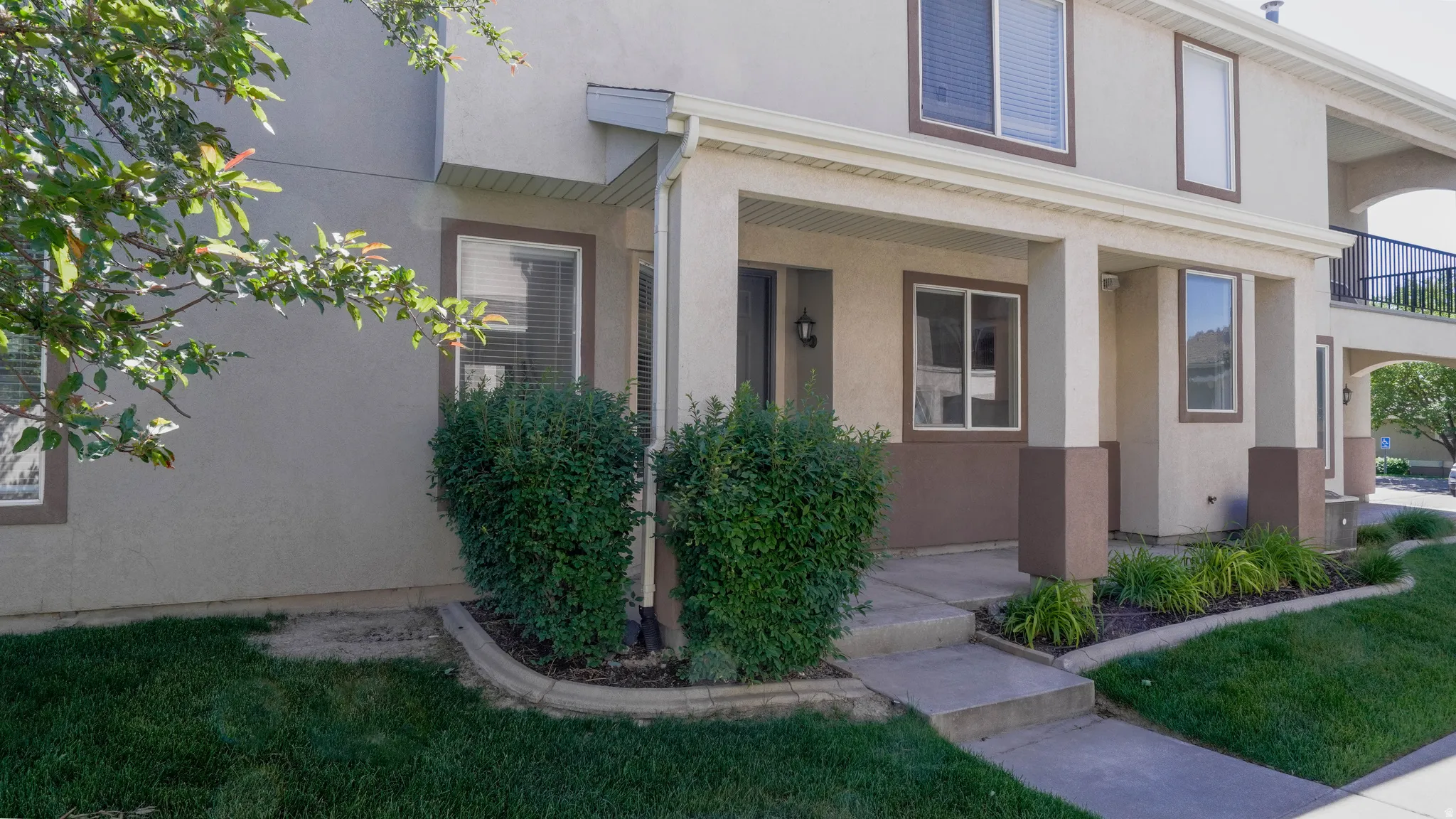 Multi-story exterior with a covered front entrance and mature landscaping