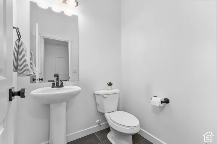 Pedestal sink featuring a dark-finish faucet, mirror, and four-bulb vanity lighting