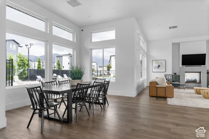 Open-concept living space featuring wood-finish flooring, a wall of large windows, a built-in fireplace with a stone-finish hearth, and recessed lighting