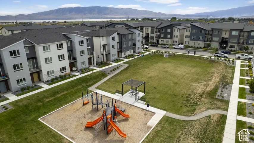 Community green space featuring a playground with orange slides, a shaded picnic area, and an expansive lawn