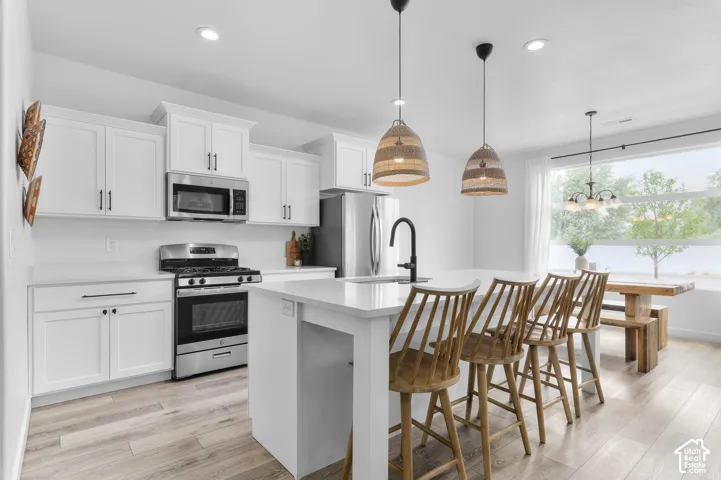 Modern kitchen featuring white cabinetry, stainless steel appliances, and a central island with a waterfall countertop