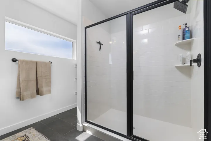 Walk-in shower with black-framed glass enclosure, white subway tile surround, integrated shelving, and a dark-finish showerhead