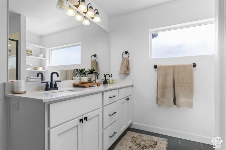 Double vanity featuring white cabinetry, black hardware, and an expansive mirror