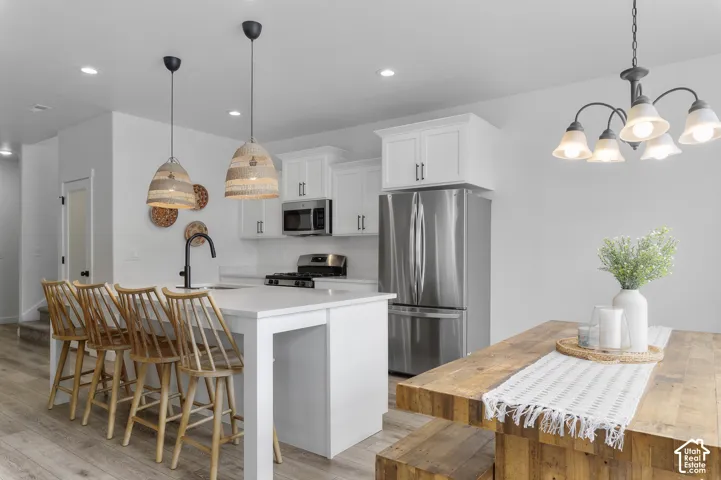 Open-concept kitchen featuring white cabinetry, stainless steel appliances, and a central island with countertop seating