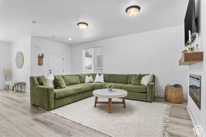 Open-concept living space featuring wood-finish flooring, white walls, and recessed lighting