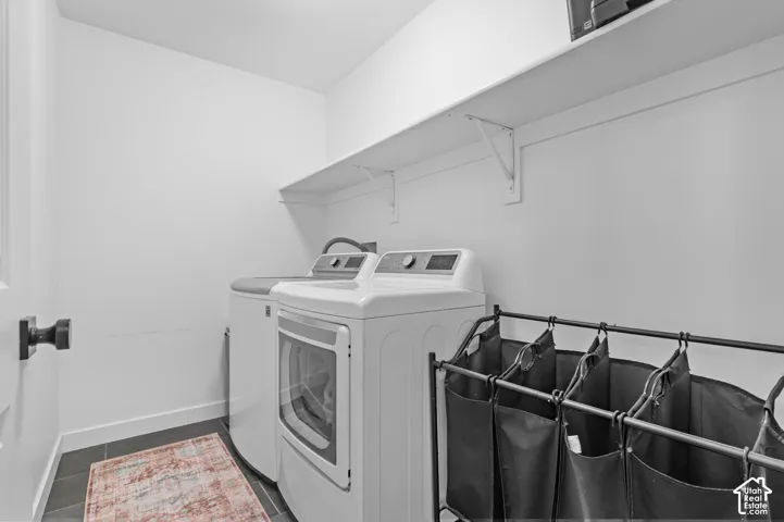 Dedicated laundry space featuring dark tile flooring and white walls
