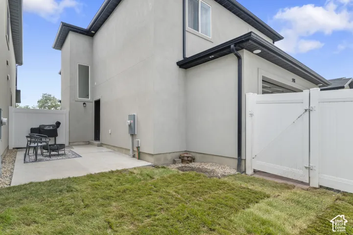 Exterior featuring a stucco finish, black gutters, and a white privacy fence