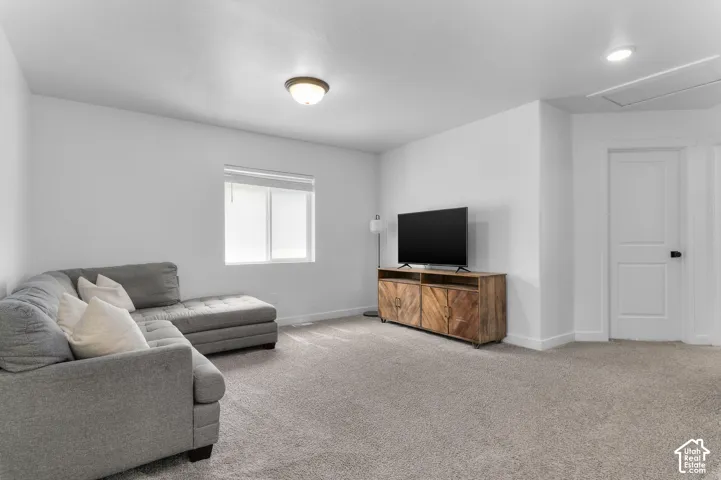 Spacious room featuring neutral carpet flooring, a white trim window with blinds, and recessed lighting