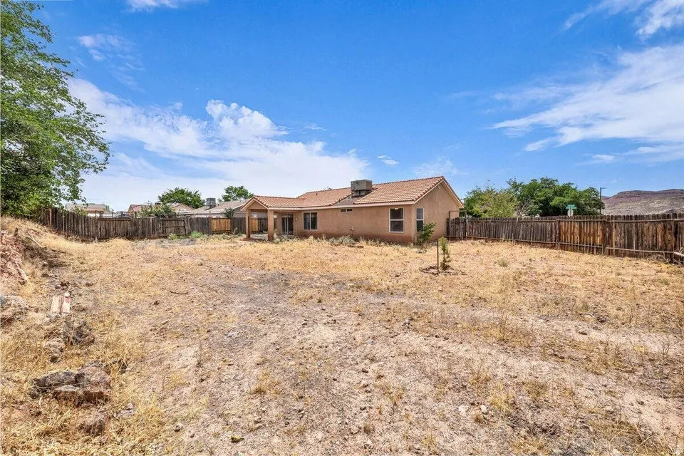 Spacious rear yard with natural landscaping and partial wood fencing