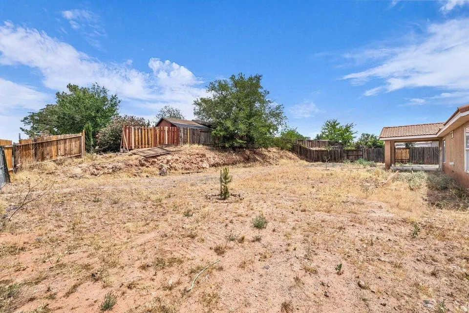 Expansive backyard with a terraced landscape, featuring a wooden privacy fence, mature trees, and a detached shed