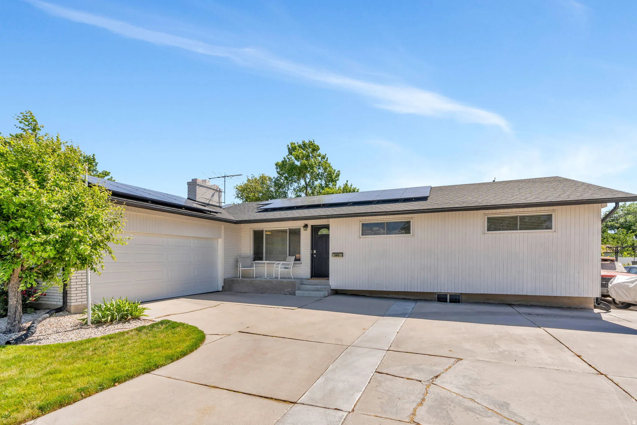 Ranch-style exterior with a dark asphalt shingle roof, white vertical siding, and a two-car garage