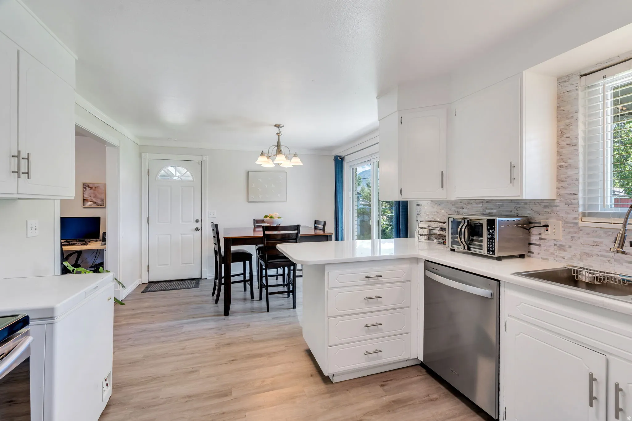 Light wood-finish flooring complements white cabinetry with brushed nickel hardware