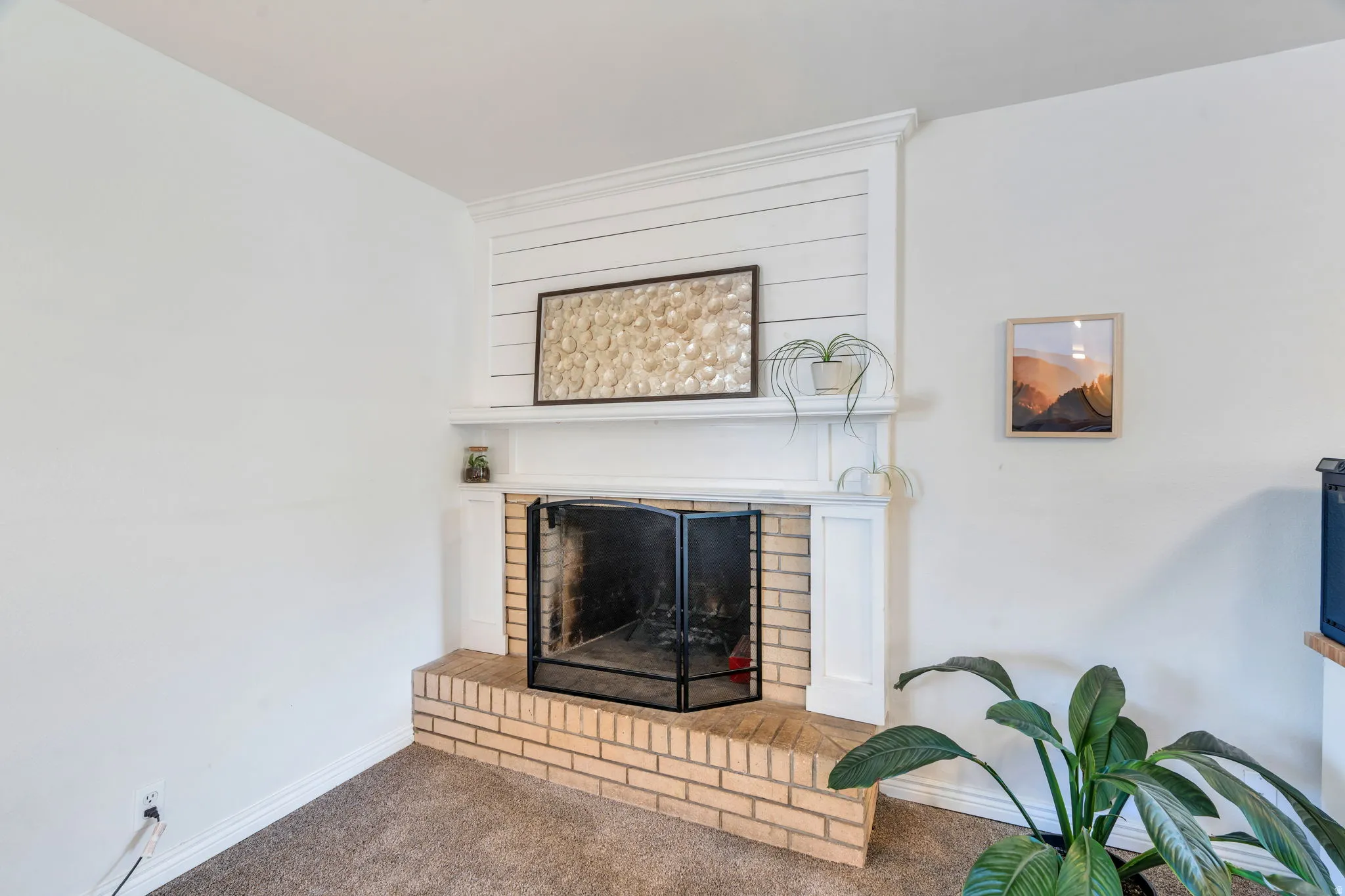 Fireplace in the front living room with a brick hearth and surround, white mantel, and shiplap-style accent