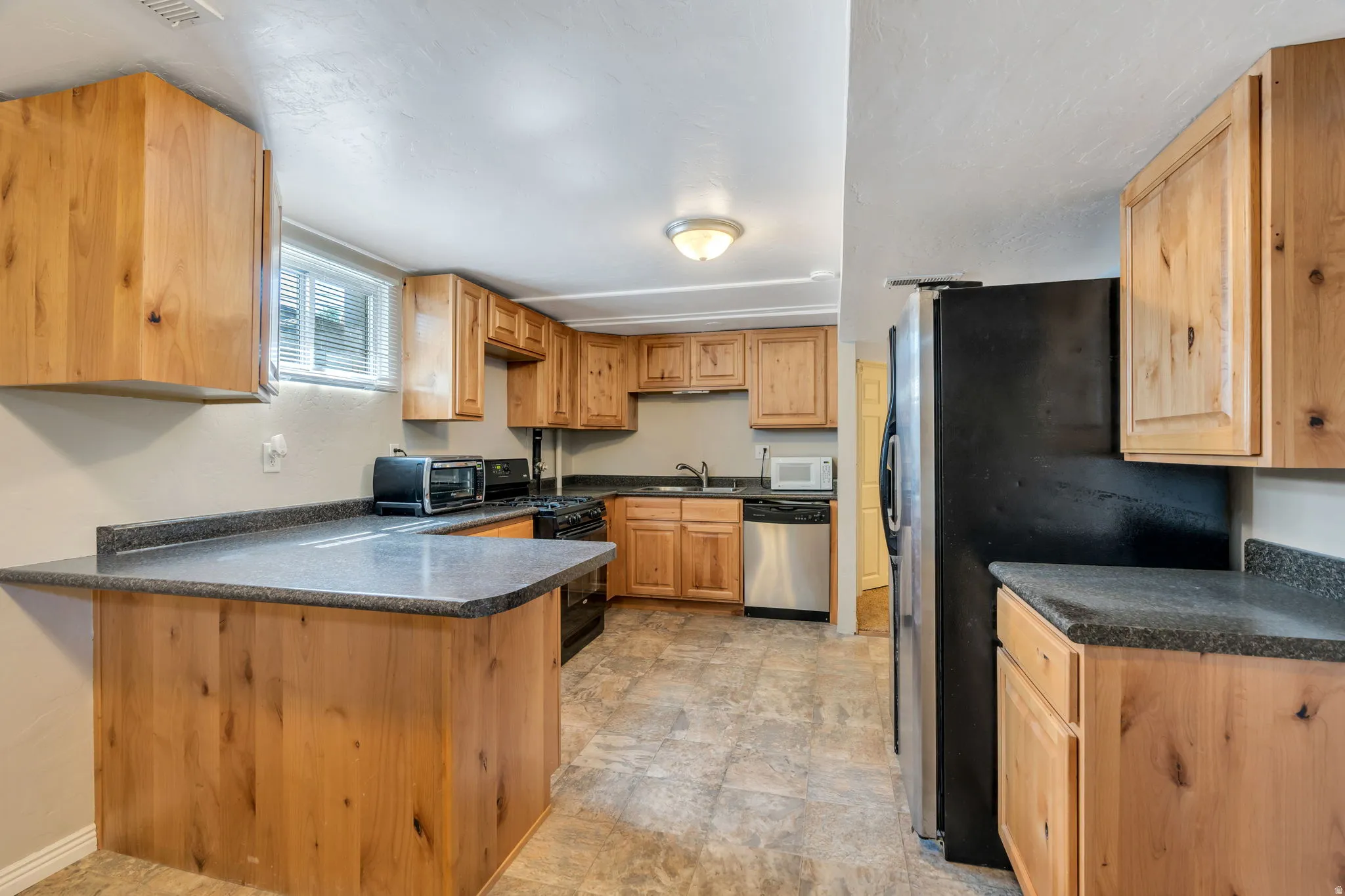 Apartment kitchen featuring knotty wood cabinetry, dark speckled countertops, and tile flooring