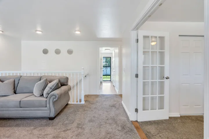 Carpeted living room featuring a white baluster railing and recessed lighting