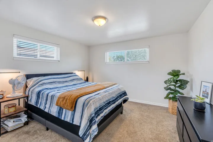 Bedroom #2 featuring neutral carpeting, white walls, two windows with blinds and a ceiling-mounted light fixture
