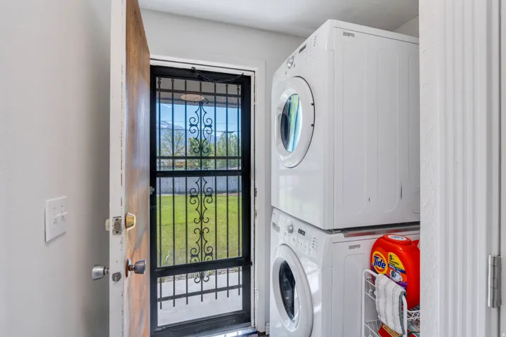 Backdoor with a screen door storm door, and a stacked white washer and dryer unit
