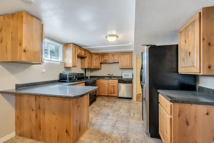 Apartment kitchen featuring knotty wood cabinetry, dark speckled countertops, and tile flooring