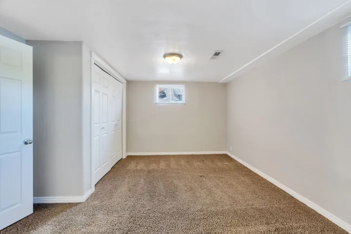 Apartment bedroom #2 with neutral-toned carpeting, two windows and a ceiling-mounted light fixture