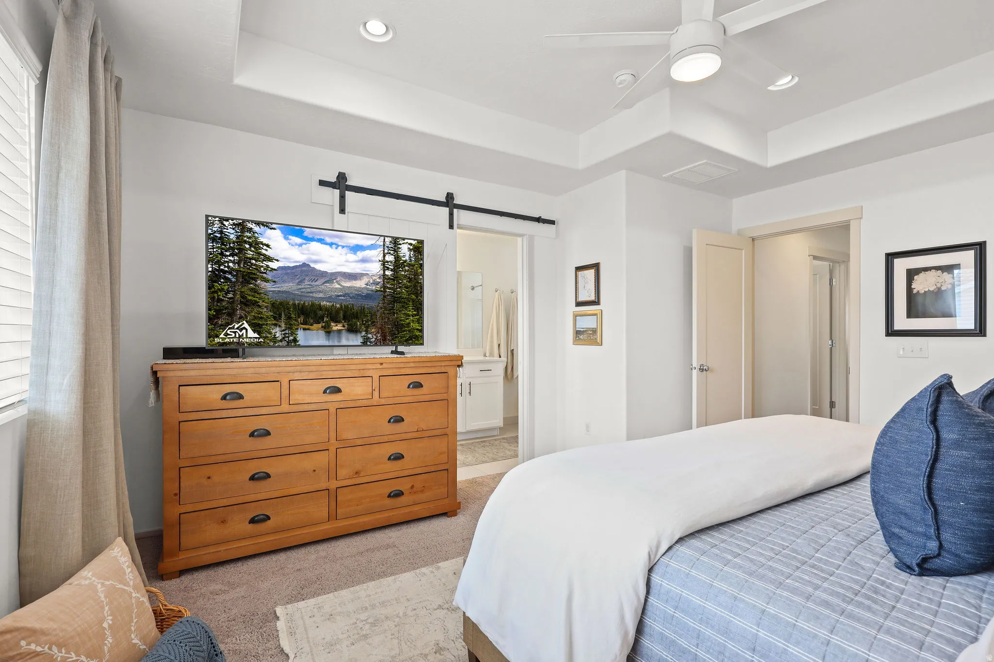 Recessed lighting and a ceiling fan illuminate this carpeted room featuring a tray ceiling