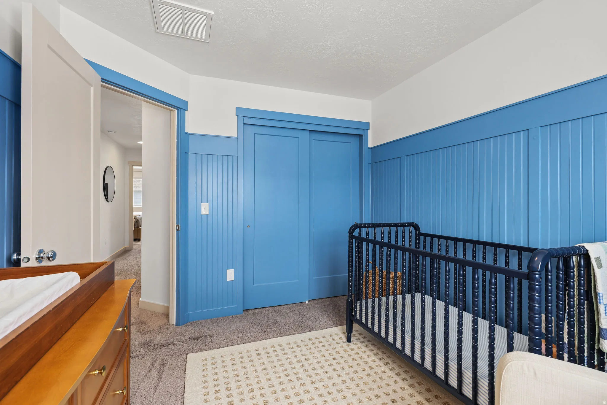 Carpeted room featuring beadboard wall paneling, a sliding closet door, and a white ceiling